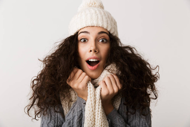 Cheerful young woman wearing winter scarf standing isolated over white background - Photo, Image