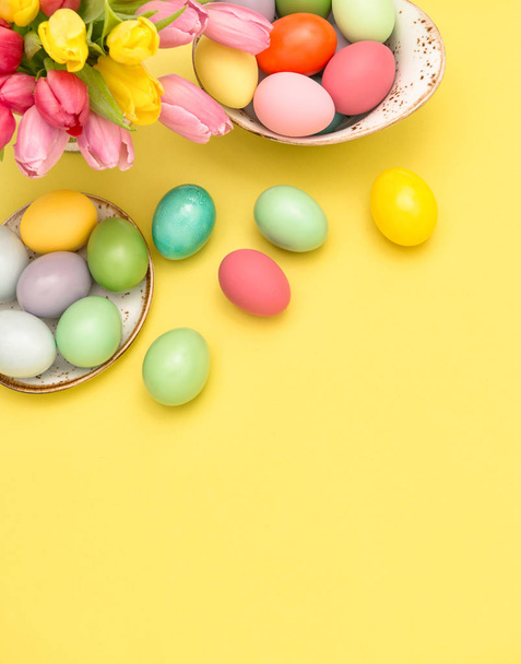 Easter eggs decoration with tulip flowers on yellow table background - Фото, зображення