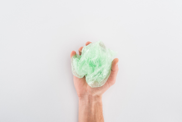 Vue partielle de l'homme tenant un sac en plastique vert sur fond gris
 - Photo, image