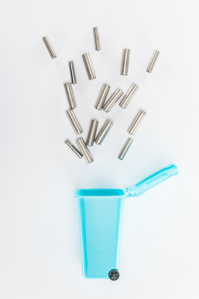 Top view of blue toy trashcan and batteries on grey background - Foto, Bild
