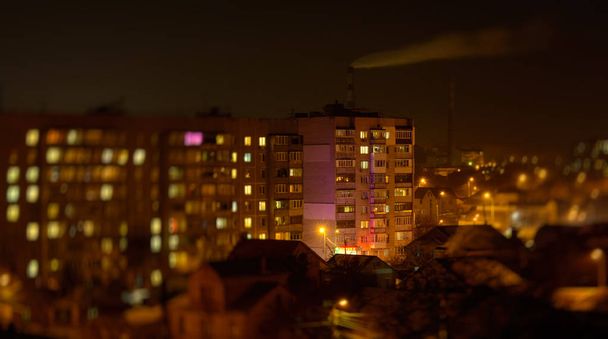 Фото міських будівель вночі з заводським димом над ними
 - Фото, зображення