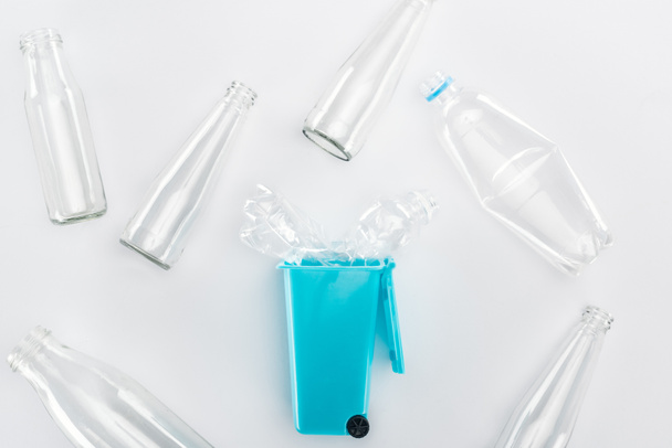 Top view of blue toy trashcan and empty plastic and glass bottles - Foto, afbeelding