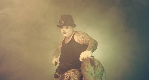 Porträt eines Zombie-Mörders mit Hut, Machete und Zombie-Köpfen posiert vor dunklem Hintergrund - Foto, Bild