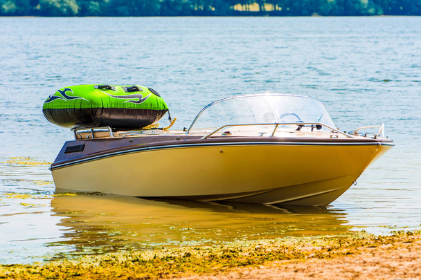 Фото белого красивого моторного резака с зеленой маленькой воздушной лодкой на реке
 - Фото, изображение