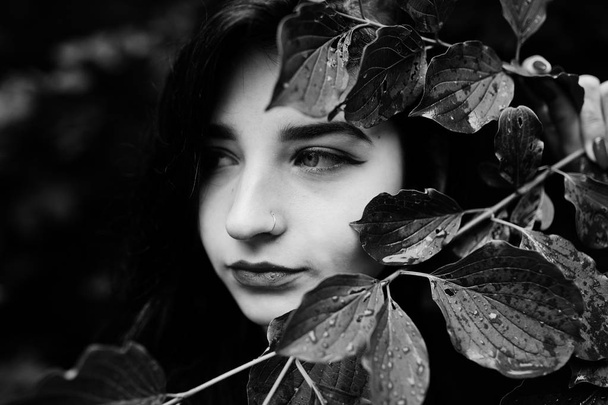 Close up portrait of sensual brunette girl with red lips. Goth dramatic woman at tree branch. Black and white. - Foto, afbeelding
