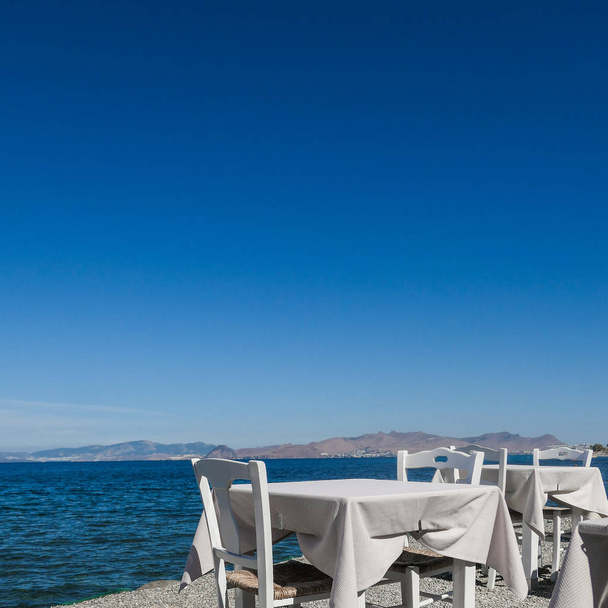 Restauracja biały tabel na plaży latem - podróże, wakacje i lato koncepcja. Doskonały lunch z widokiem na morze - Zdjęcie, obraz