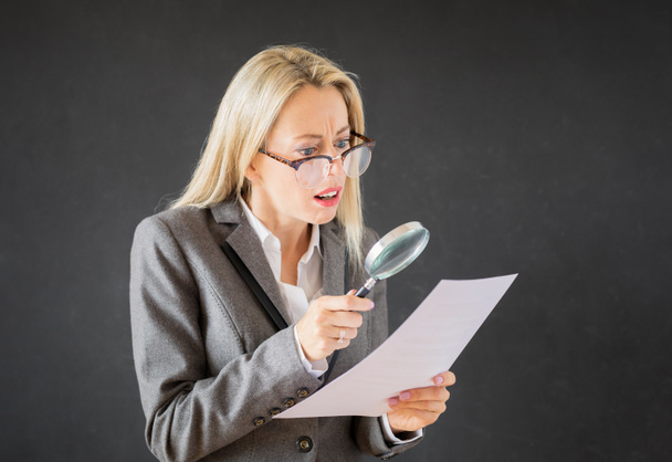 Frau liest Geschäftsvertrag mit Lupe - Foto, Bild