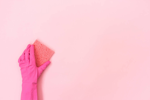 Mujer con guantes de goma sosteniendo una pequeña esponja para lavarse en la mano aislada sobre fondo rosa pastel con espacio vacío para el texto
 - Foto, imagen