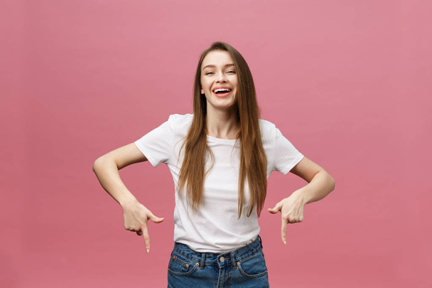 Photo of happy young woman standing and poiting finger isolated over pink background - Photo, Image