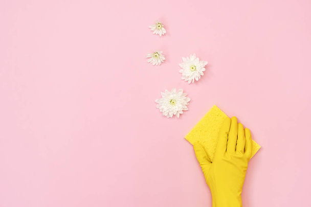 Жінка в жовтих гумових рукавичках тримає м'яку губку для миття в руці ізольовано на пастельно-рожевому тлі з квітами і порожнім місцем для тексту
 - Фото, зображення