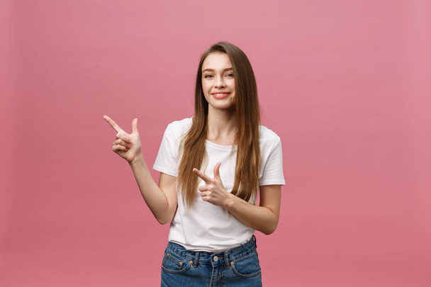 Foto van gelukkige jonge vrouw staande en wijzende vinger geïsoleerd over roze achtergrond. - Foto, afbeelding