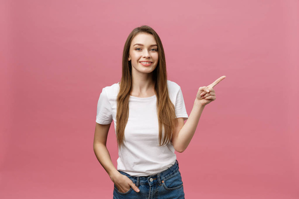 Photo of happy young woman standing and poiting finger isolated over pink background. - Φωτογραφία, εικόνα