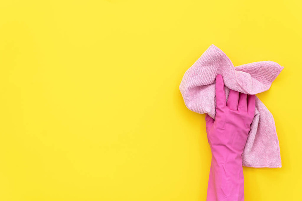 Femme en gants de caoutchouc rose coloré tenant serviette de nettoyage dans sa main isolé sur fond jaune avec espace vide pour le texte
 - Photo, image