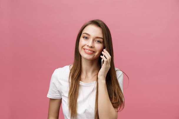 Cheerful young woman talking on mobile phone isolated on pink background - Photo, Image