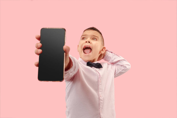 Indoor portrait of attractive young boy holding blank smartphone - Фото, изображение