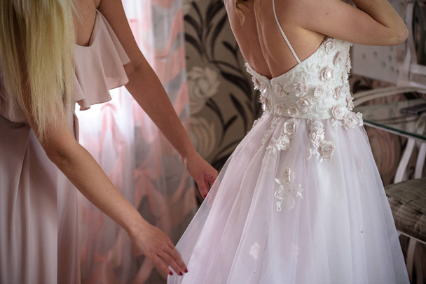 花嫁介添人の結婚式の日の花嫁を準備します。式の前に花嫁のウェディング ドレスを留めることができます。高級ブライダル ドレスをクローズ アップ。結婚式のコンセプト. - 写真・画像