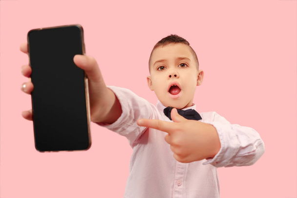Indoor portrait of attractive young boy holding blank smartphone - Zdjęcie, obraz