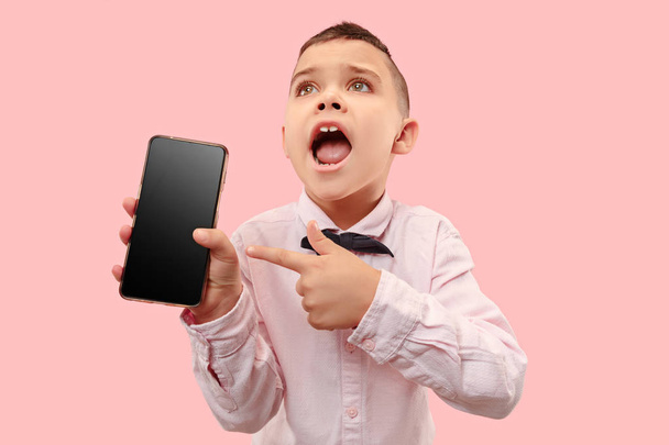Indoor portrait of attractive young boy holding blank smartphone - Φωτογραφία, εικόνα