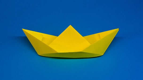 Origami, yellow ship of paper on blue background, hobby - Zdjęcie, obraz