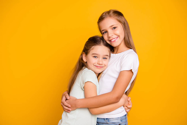 Portrait of two nice-looking cute adorable sweet attractive lovely pretty cheerful positive healthy straight-haired girls cuddling isolated over bright vivid shine yellow background - Fotografie, Obrázek