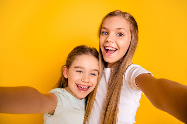 Self-portrait of nice-looking cool cute crazy attractive lovely winsome cheerful cheery positive emotional pre-teen girls having fun isolated over bright vivid shine yellow background - Foto, imagen