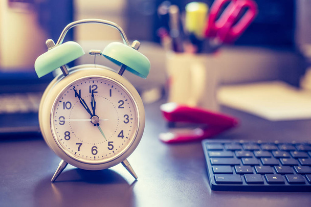 Alarm clock on the desk, office stuff in the blurry background, deadlines and todos - 写真・画像