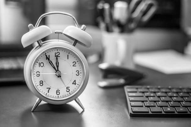 Alarm clock on the desk, office stuff in the blurry background, deadlines and todos - 写真・画像
