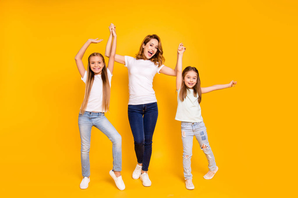 Full length body size view portrait of three nice cute attractive stylish healthy slim cheerful people holding raising hands mum mommy win winner isolated over bright vivid shine yellow background - Foto, afbeelding