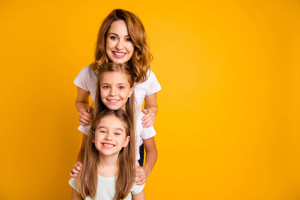 Portrait of three nice cute adorable lovely lovable attractive cheerful positive funny people standing in order of height having fun isolated over bright vivid shine yellow background - Фото, зображення