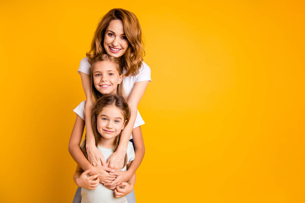 Portrait of three nice cute lovely attractive adorable cheerful positive funny blonde people standing in order of height leisure support isolated over bright vivid shine yellow background - Foto, afbeelding