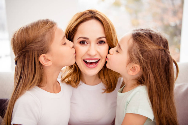 Close-up portrait of nice cute lovely winsome sweet gentle tender attractive charming cheerful cheery positive glad redhair people mom kissing pre-teen girls in house indoors - Foto, immagini