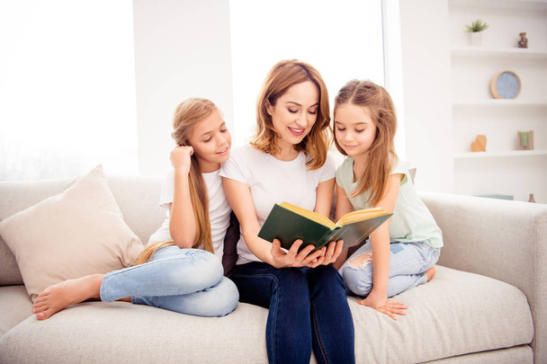 Portrait of nice cute lovely attractive charming cheerful cheery red hair people mom reading book pre-teen girls sitting on divan in house indoors - Fotó, kép