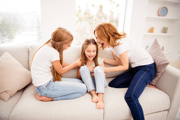 Portrait of nice cute lovely attractive adorable cheerful cheery positive funny funky blonde hair  people mom mommy mum pre-teen girls playing on divan rejoicing in house indoors - Fotó, kép