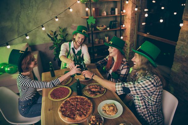 Close up photo gathered big table company four friends couples pairs love lovers tasty drinks green hats leaf pizza sausage chips irish culture home party leprechaun costumes  - Foto, Bild
