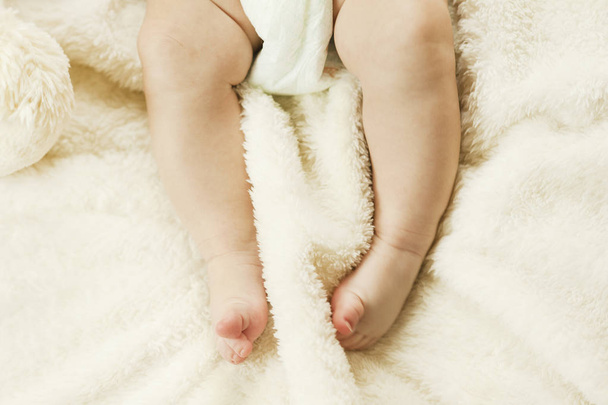 kleine zachte gezonde benen van een pasgeboren baby knagen op een plaid. Gezonde kinderen concept - Foto, afbeelding