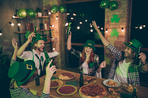 Close up photo people two couples green beverage hold in air hats leaf eat food pizza sausage chips leprechaun costumes checkered plaid shirt rest relax together weekend vacation free time leisure - Photo, Image