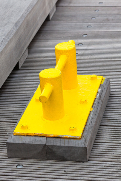 Крупный план Bright Yellow Boat Cleat на причале
 - Фото, изображение