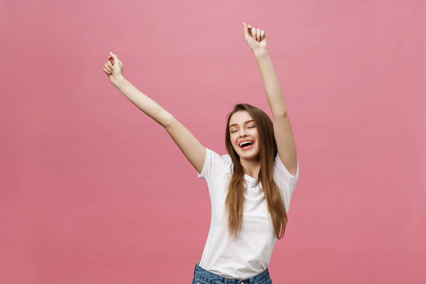 Счастливая успешная молодая женщина с улыбкой, кричать и праздновать успех на розовом фоне - Фото, изображение