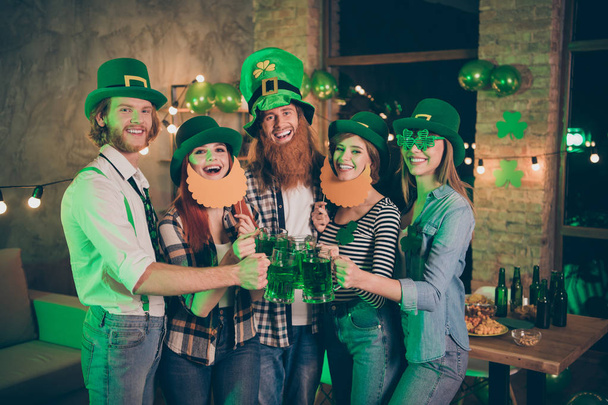 Group buddies company hands arms raise alcohol wear specs national culture costumes tradition hats checkered plaid jeans shirts lucky leaf false beard mustache laugh laughter toasting - Foto, imagen
