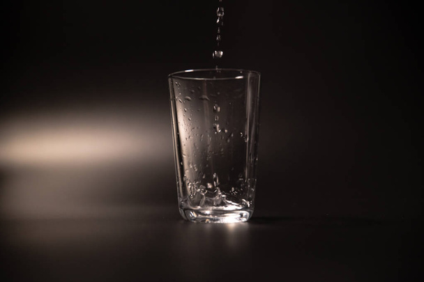 On a black background in a glass of water poured - Zdjęcie, obraz
