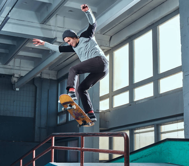 Jonge skateboarder uitvoeren van een truc op mini hellingshoek op indoor Skatepark.  - Foto, afbeelding