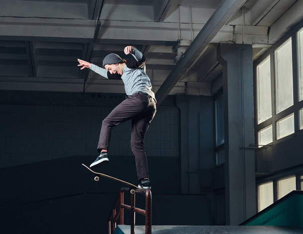 Młody Skater wykonywanie trick na ziemi mini skate park kryty.  - Zdjęcie, obraz
