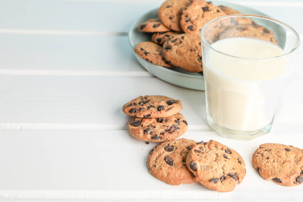 Tasty chocolate chip cookies and glass of milk on wooden table. Space for text - Fotoğraf, Görsel