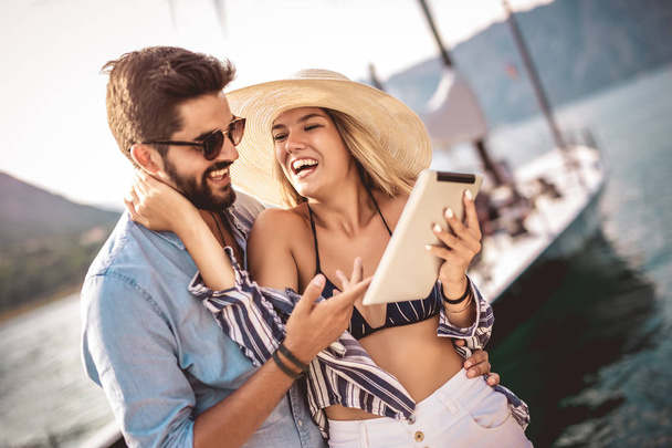 Couple amoureux, profiter de l'heure d'été en bord de mer à l'aide d'une tablette numérique
. - Photo, image
