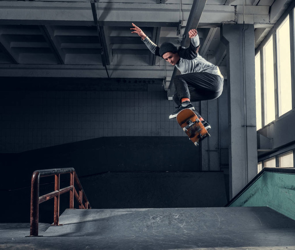 Young skateboarder performing a trick on mini ramp at skate park indoor.  - 写真・画像