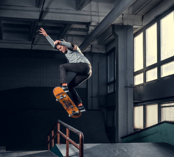 Young skateboarder performing a trick on mini ramp at skate park indoor.  - Fotó, kép