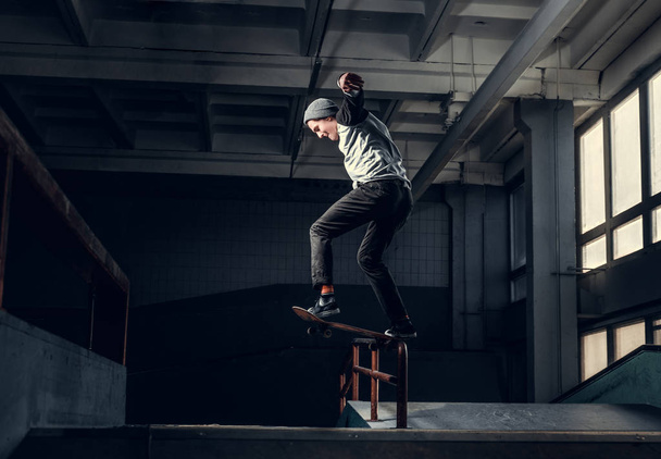 Jovem skatista executando um truque em mini rampa no parque de skate indoor
.  - Foto, Imagem