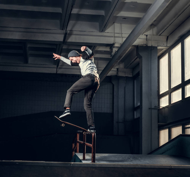 Jonge skateboarder uitvoeren van een truc op mini hellingshoek op indoor Skatepark.  - Foto, afbeelding