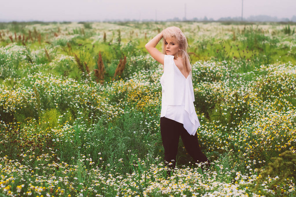 Portrait of young girl staying in chamomile field with hands on head - Fotoğraf, Görsel