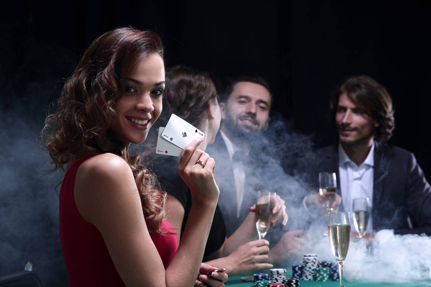young brunette woman playing poker on black background - Fotó, kép